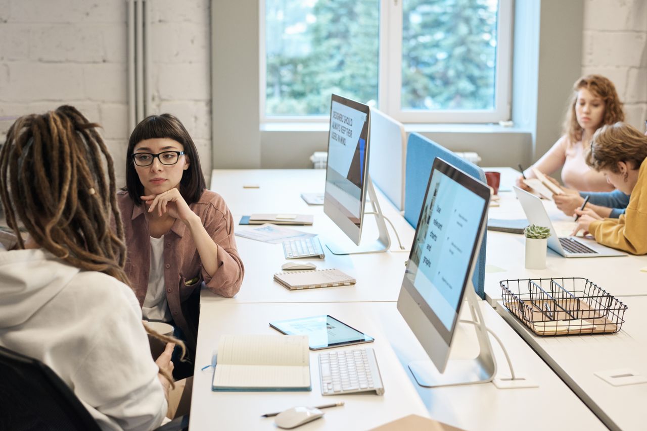 heros-img Diverse group of women working together in a modern office setting, fostering teamwork and creativity.